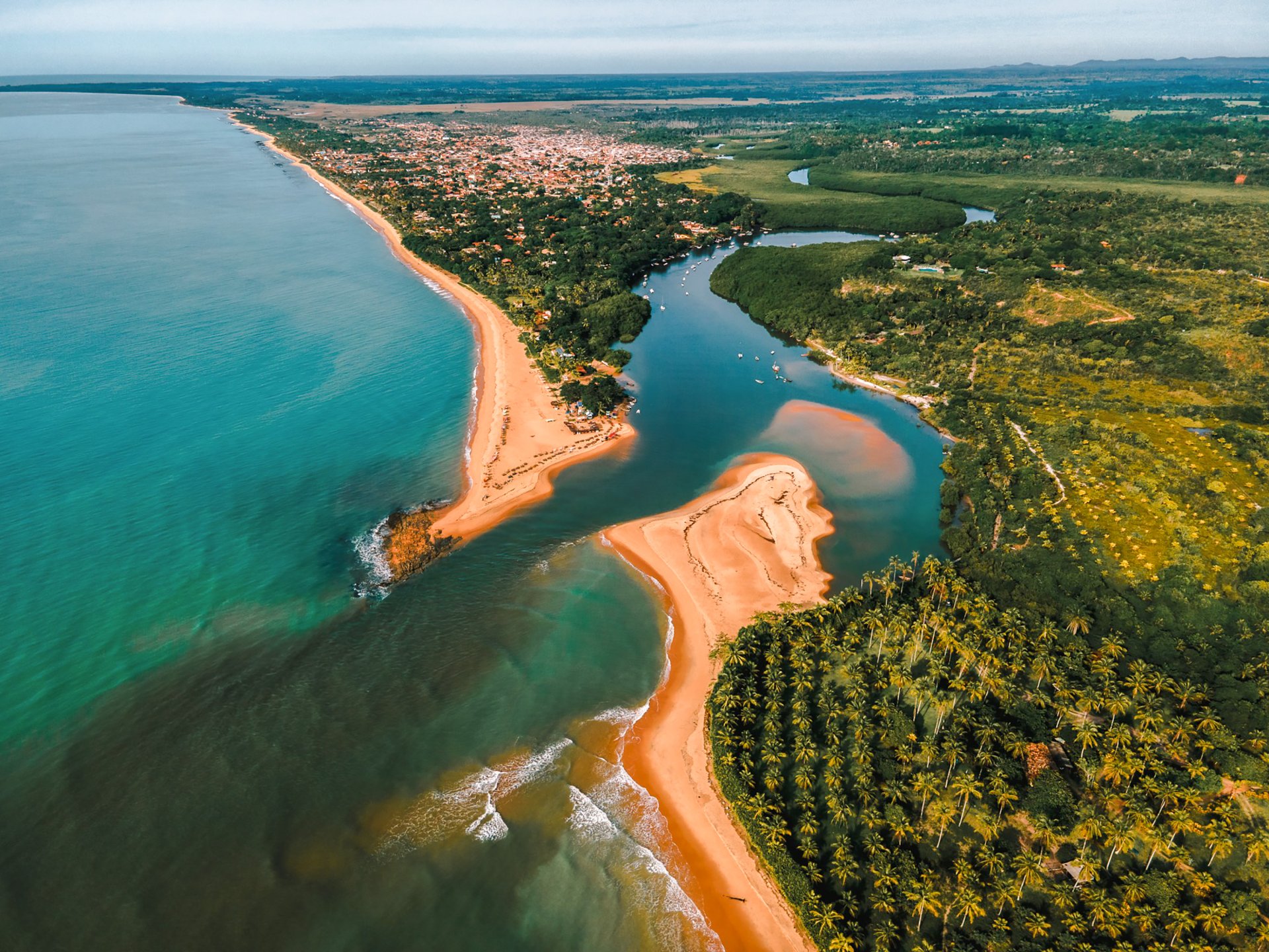 Encontro do rio Cara&iacute;va com o mar, cercado pela vila e pela natureza